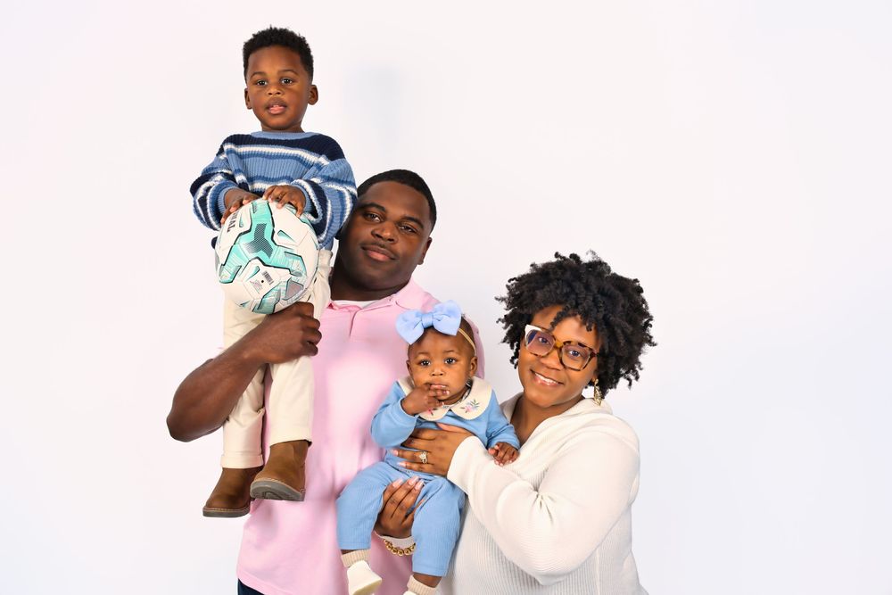 A happy family poses together against a white background wearing casual clothing.