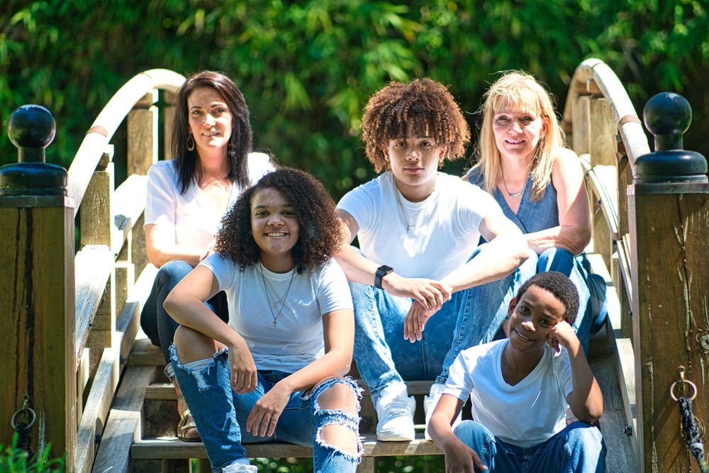 Group of friends sitting together on a wooden bridge outdoors on a sunny day.