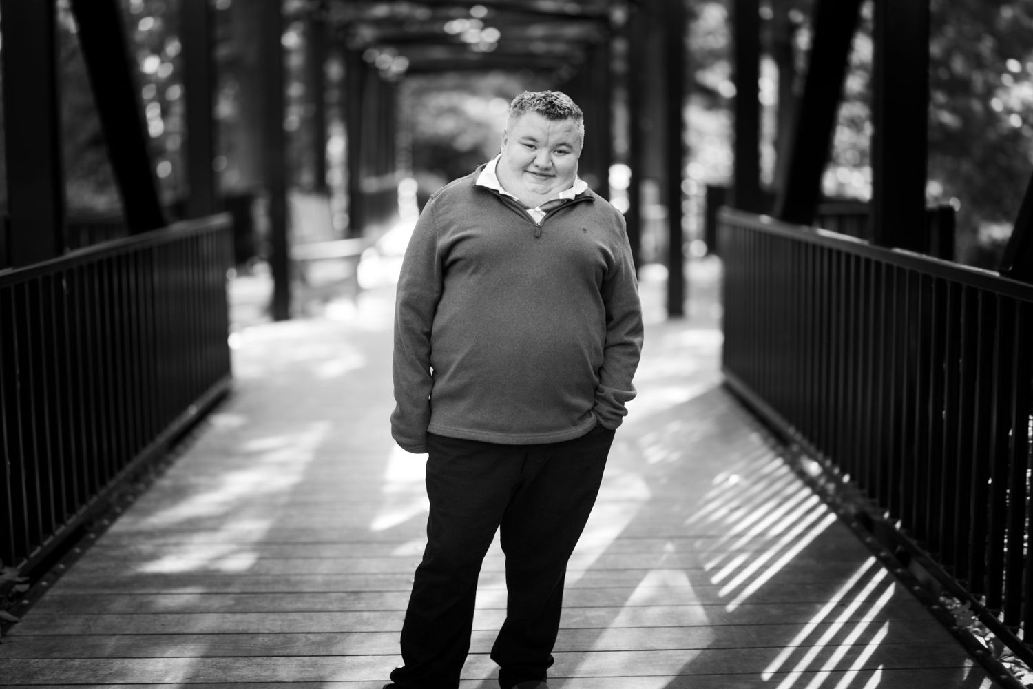 Black and white portrait of a senior in the center of a bridge with a shy smile, but a bold surrounding.