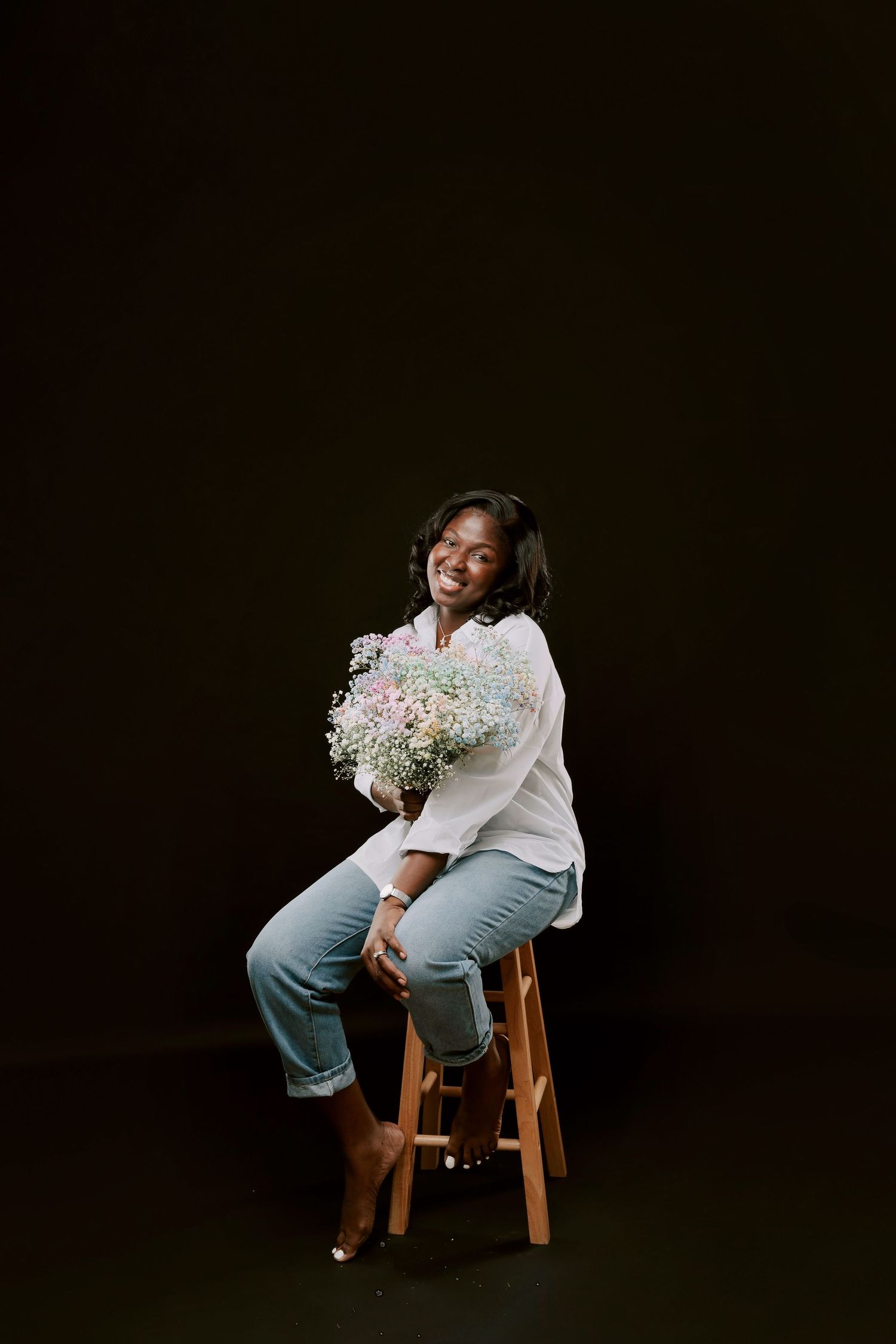 Glamour studio photo of a beautiful black woman wearing a casual fit on her 40th Birthday holding colourful flowers