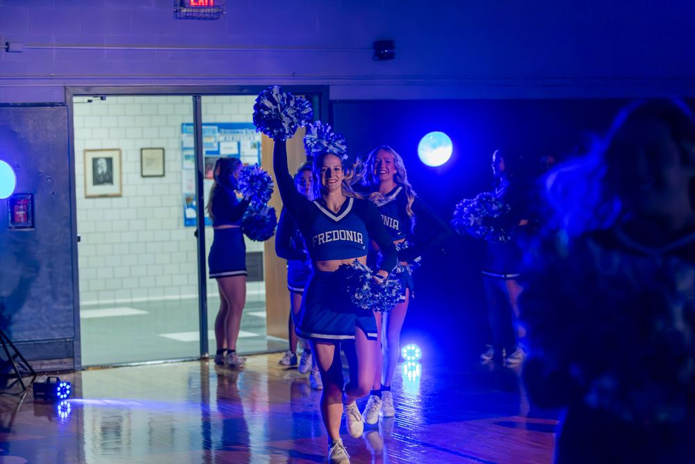 Athletes entering a darkened gymnasium with dramatic blue lighting effects.