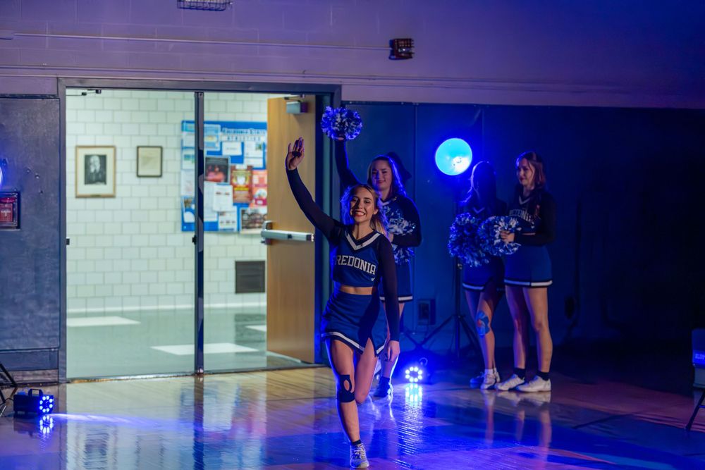 Team members lined up in a dimly lit gymnasium with blue spotlights.