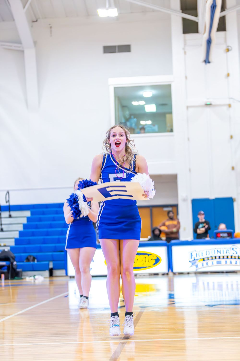 Cheerleader executes a spirited routine on a polished basketball court.