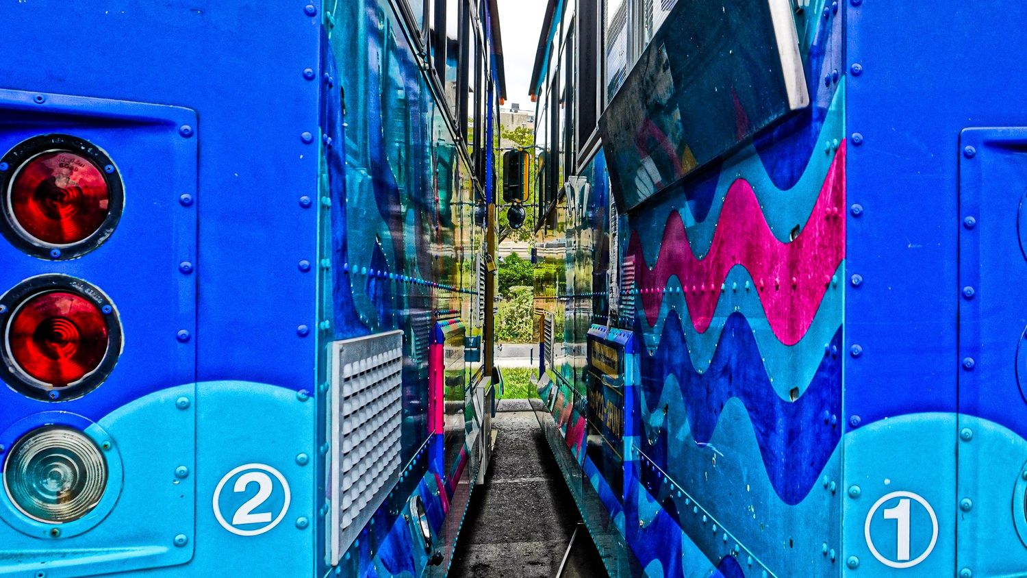 Close-up view between two blue trains showing colorful zigzag patterns and numbered markers.