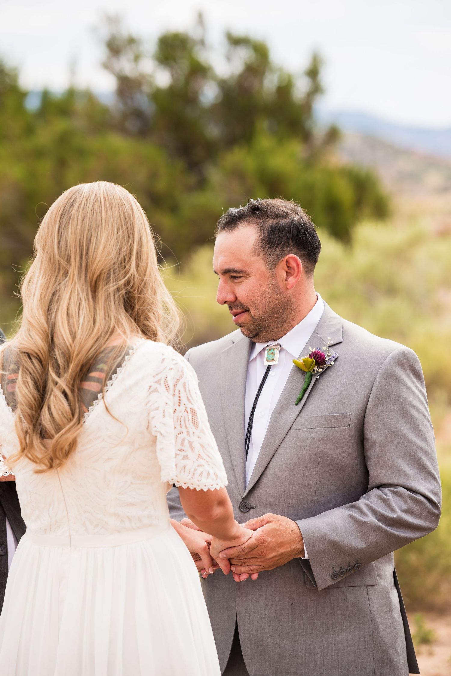 An intimate outdoor wedding ceremony moment captured against a desert mountain backdrop.