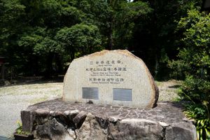 Stone monument with Japanese text inscriptions in a natural park setting.