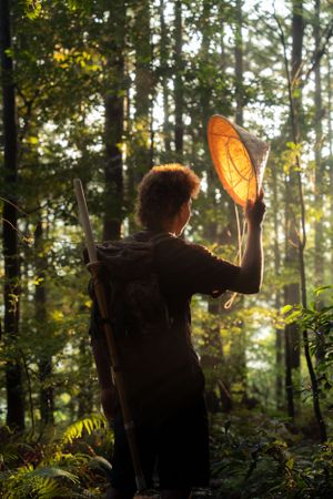 Silhouettes of figures in a sunlit forest during golden hour creating a magical atmosphere.