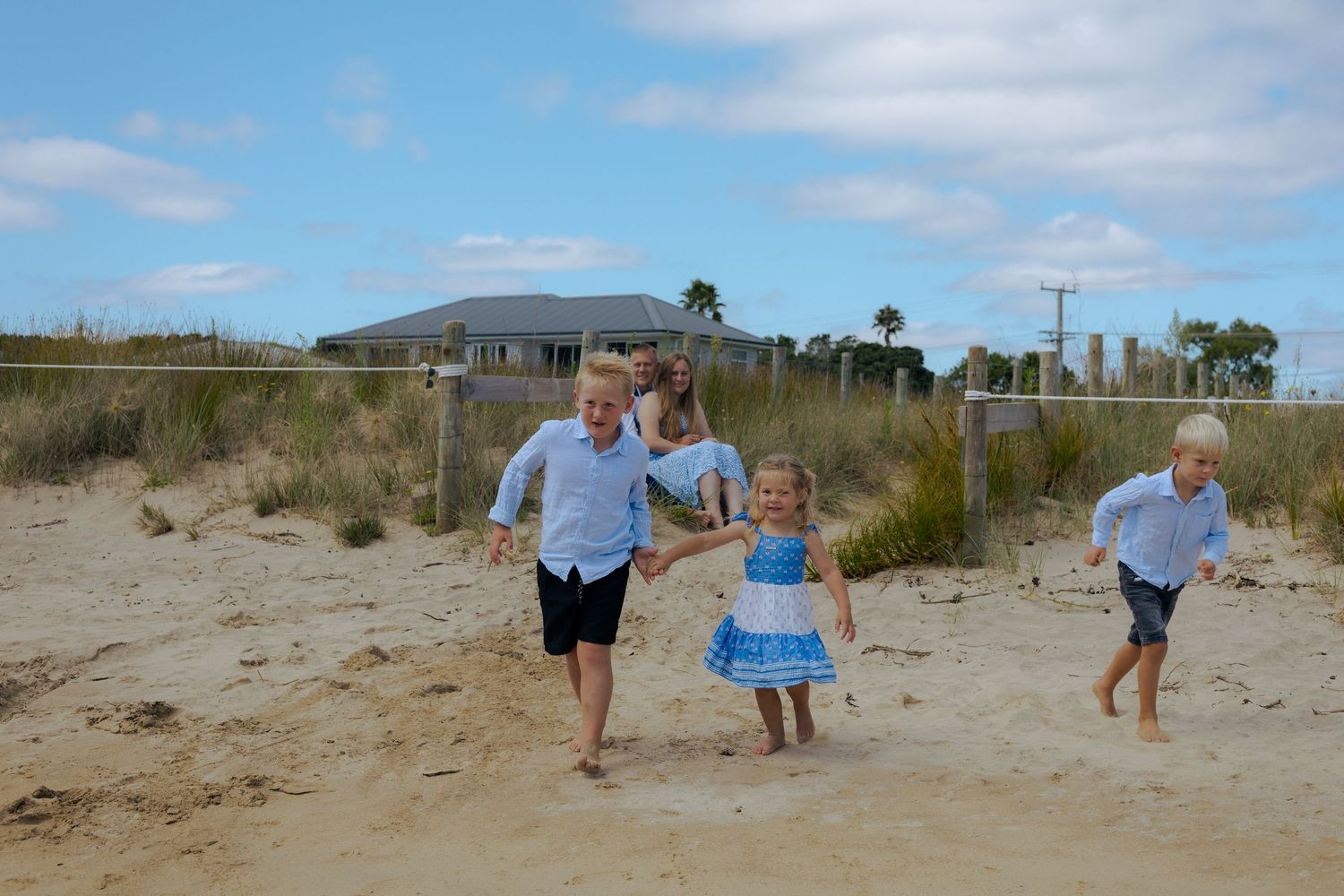 Family walking together holding hands on a pristine white sand beach with rocky cliffs.