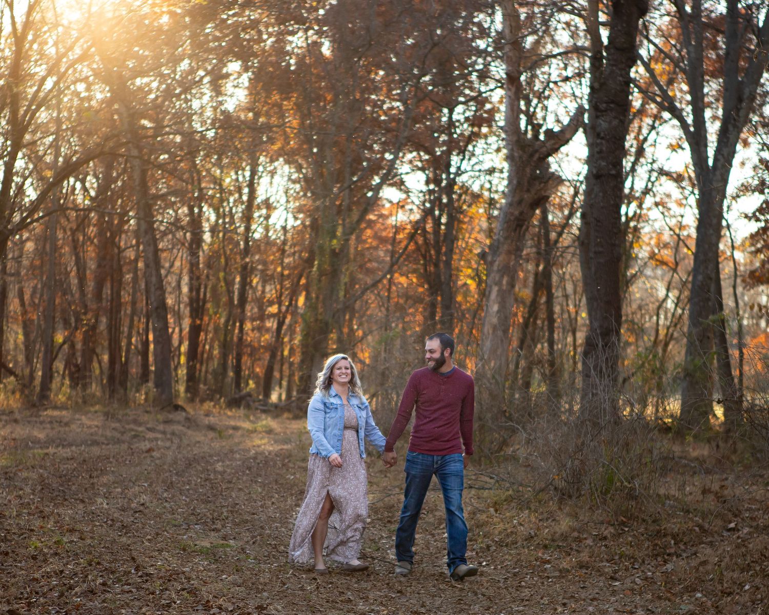 Couple walking together in sunlit autumn forest.