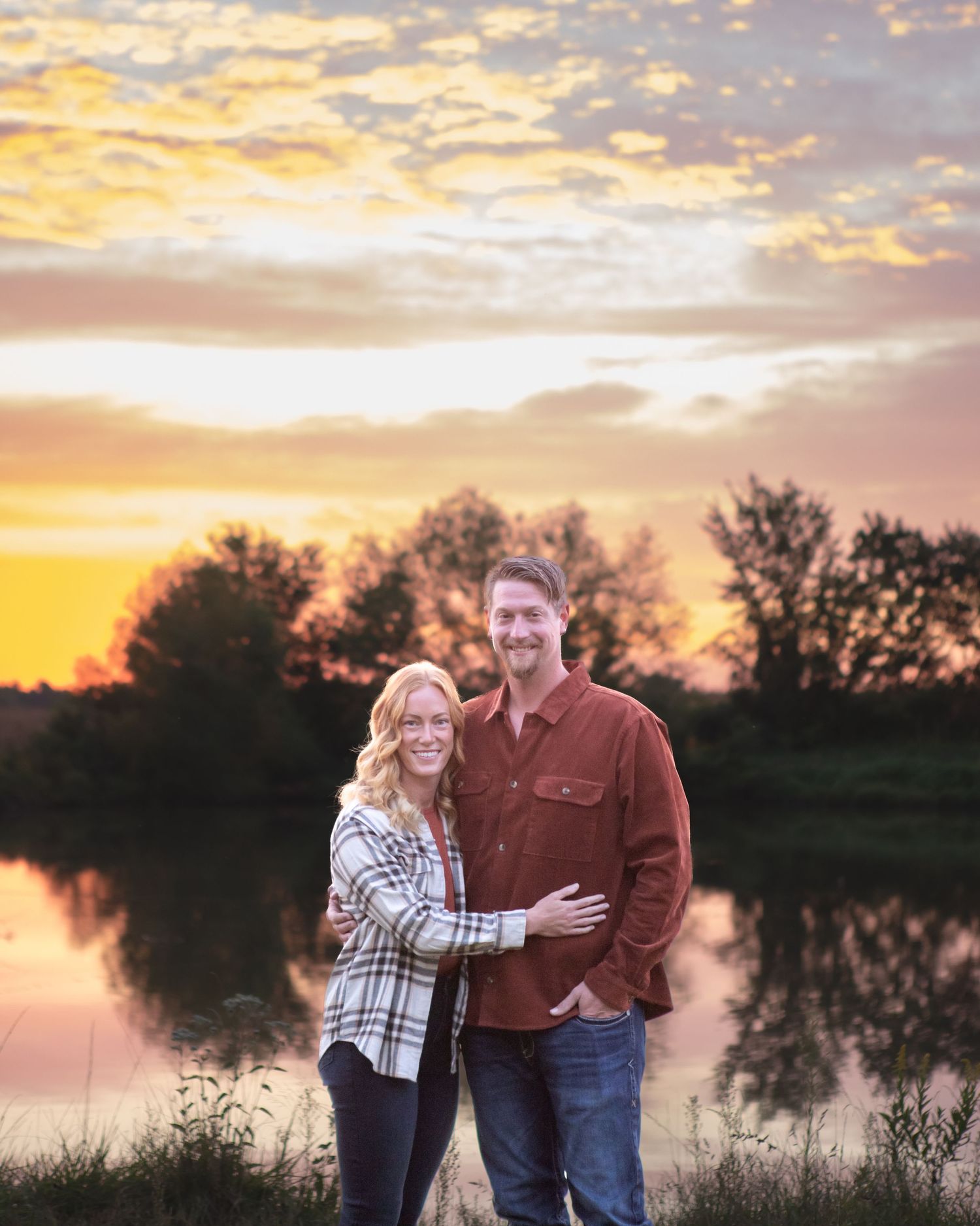 Couple enjoying a romantic sunset by a reflective lake.