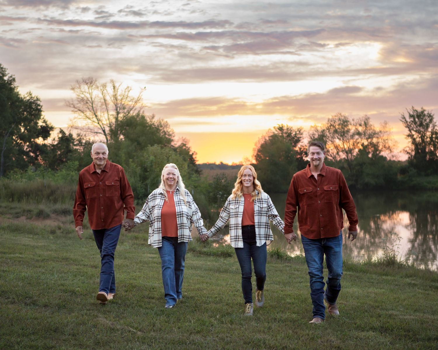 Family walking together during sunset near a tranquil lake.