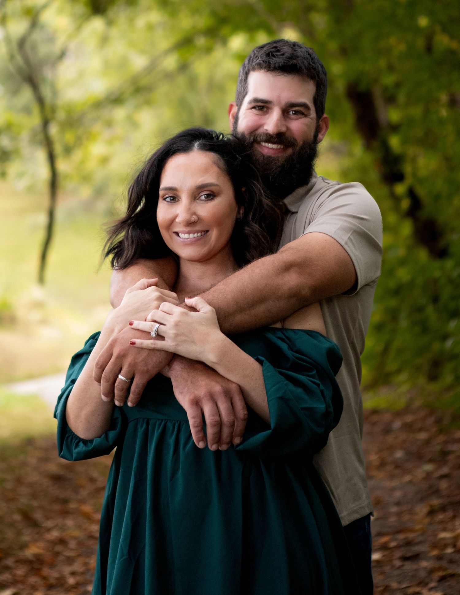 A couple embraces while sharing a romantic moment in a wooded setting.