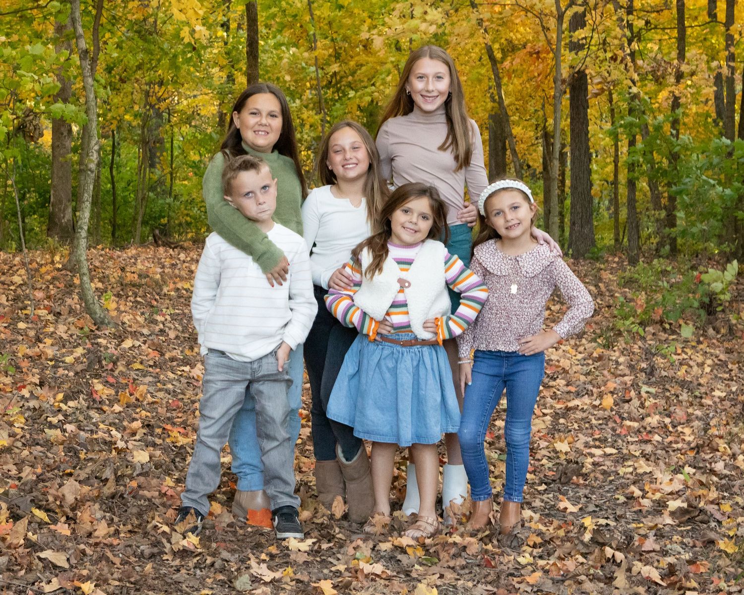 Group portrait session in a vibrant autumn forest with golden leaves and natural lighting.