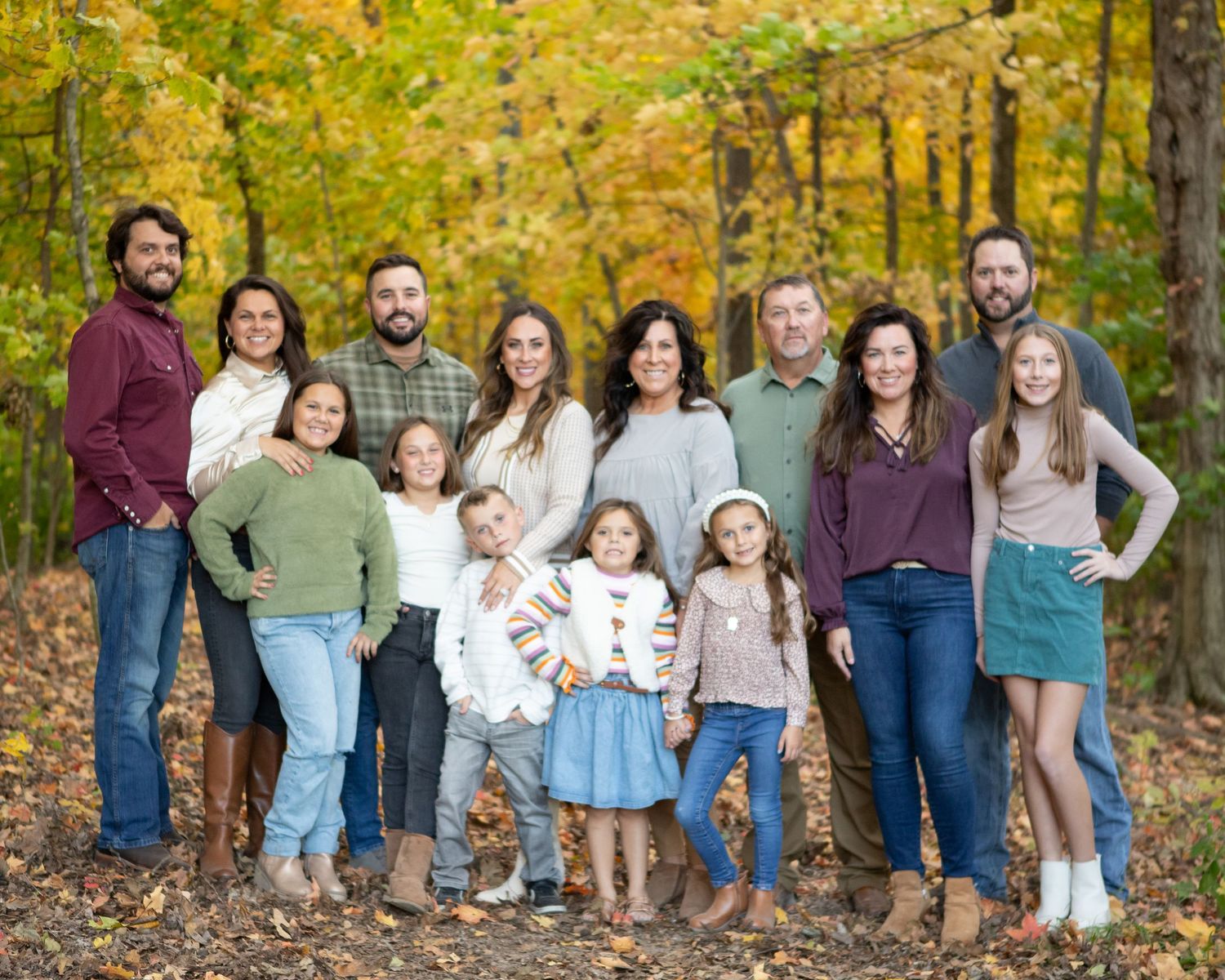 Extended family group photo against colorful fall foliage background.
