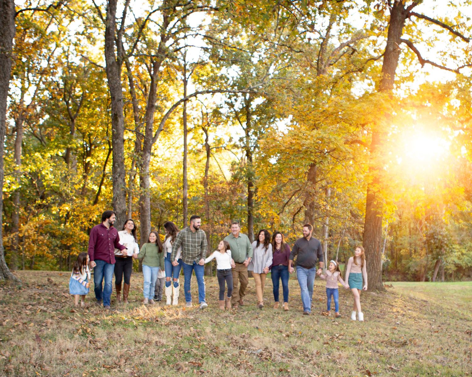 Multiple families gathered for sunset portraits in a golden-lit autumn field.