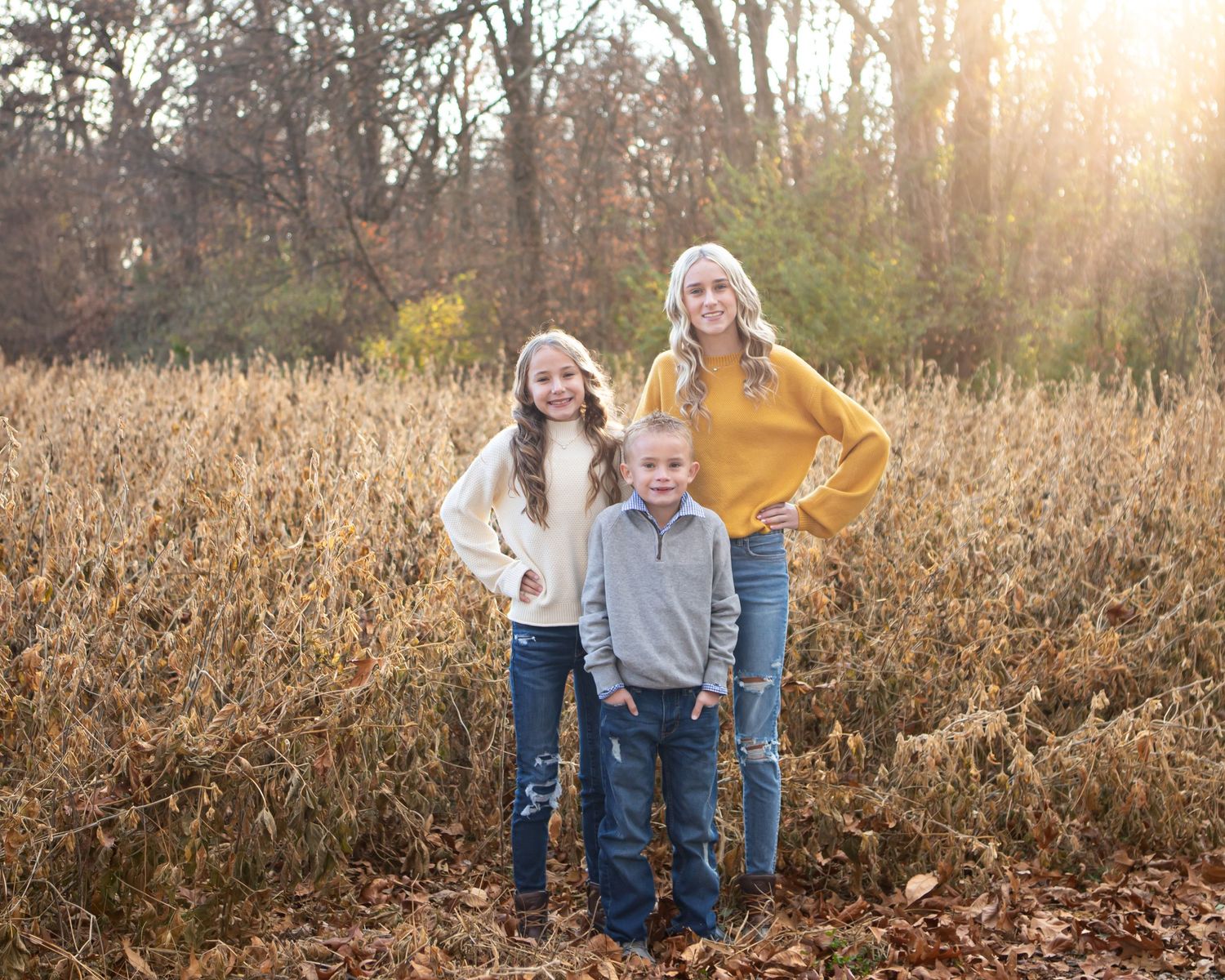 Casual family portraits with sun flare in tall autumn grass.