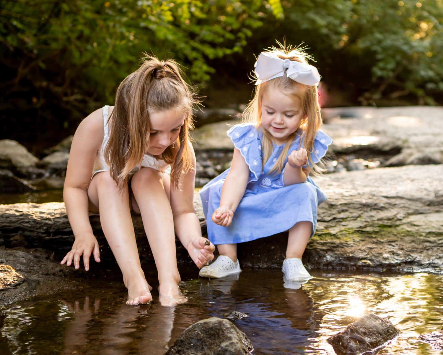Children playing and exploring by water's edge during outdoor photo session.
