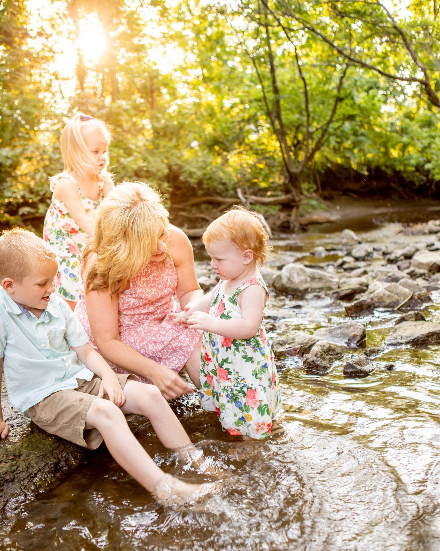 Children splash and play in a sunlit creek on a summer day.