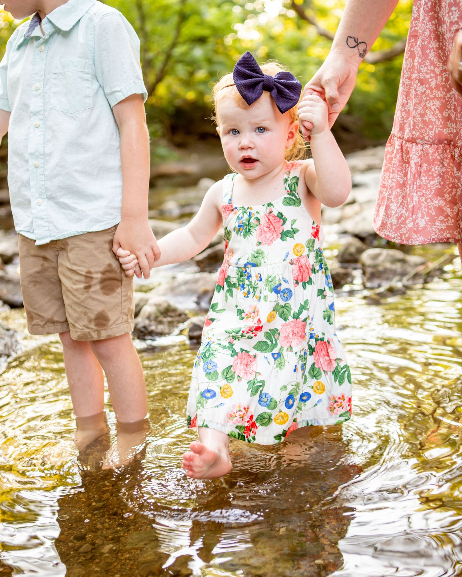 Children's feet splash in shallow creek water wearing summer outfits.