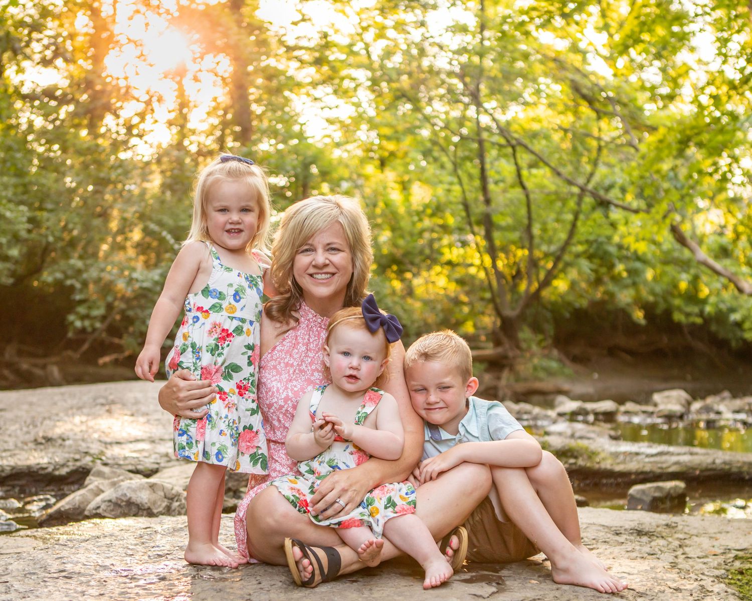 A group sits together on rocky ground surrounded by lush greenery and trees.