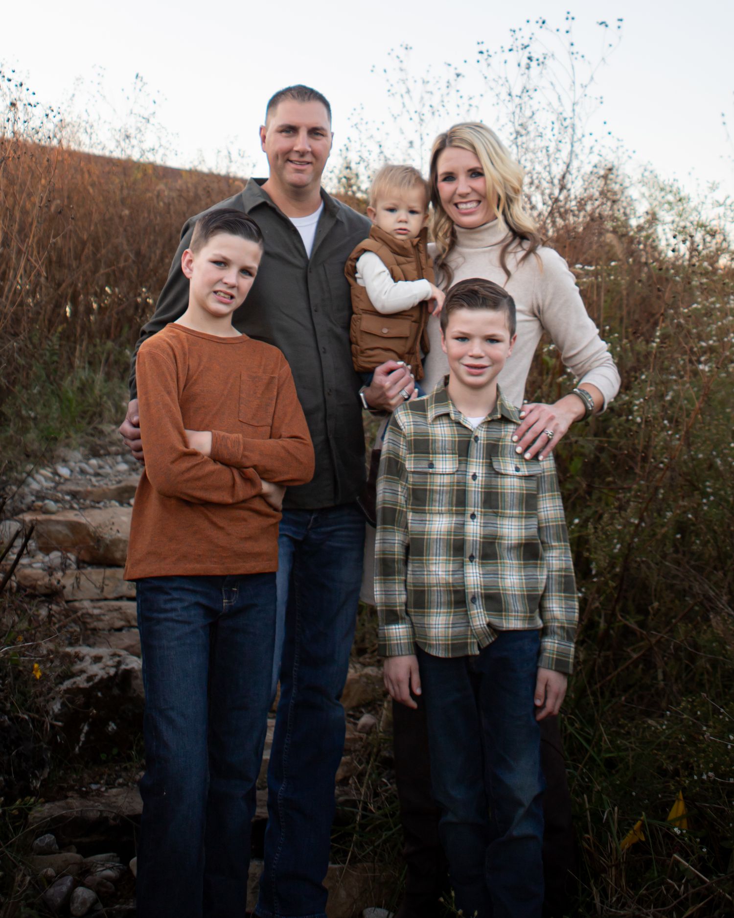 Family group poses together against autumn foliage during an outdoor portrait session.