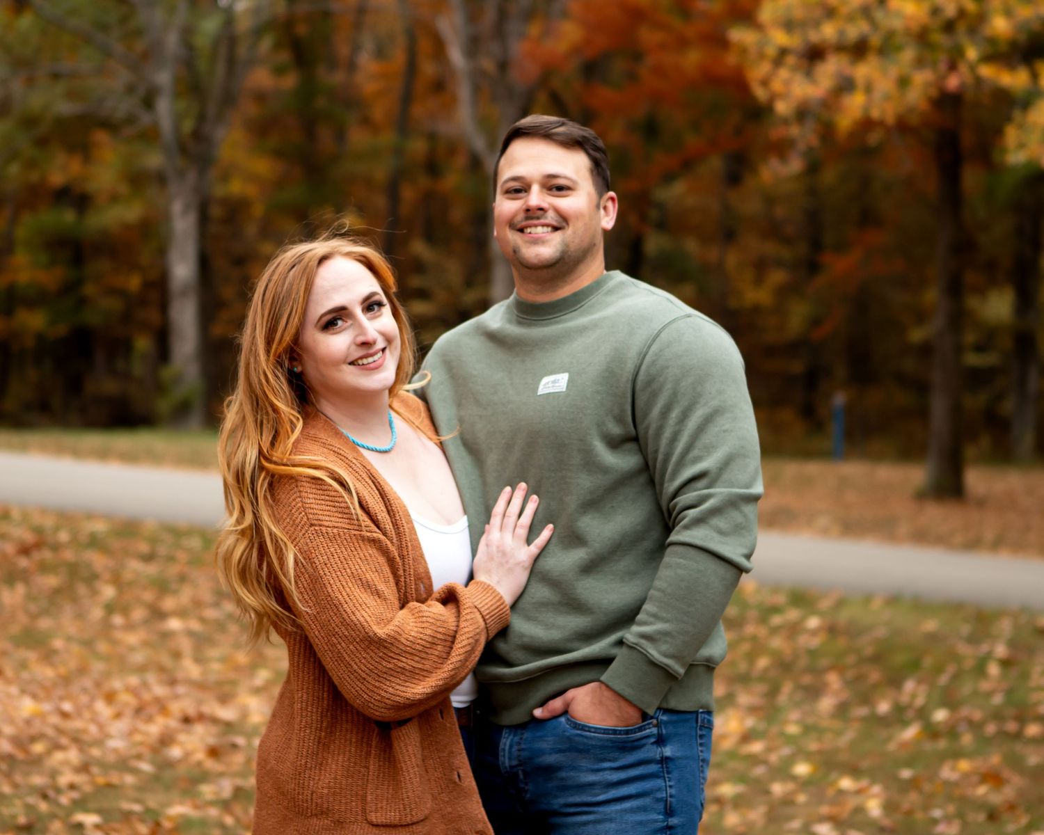 Couple embracing in romantic autumn setting with fallen leaves in background.