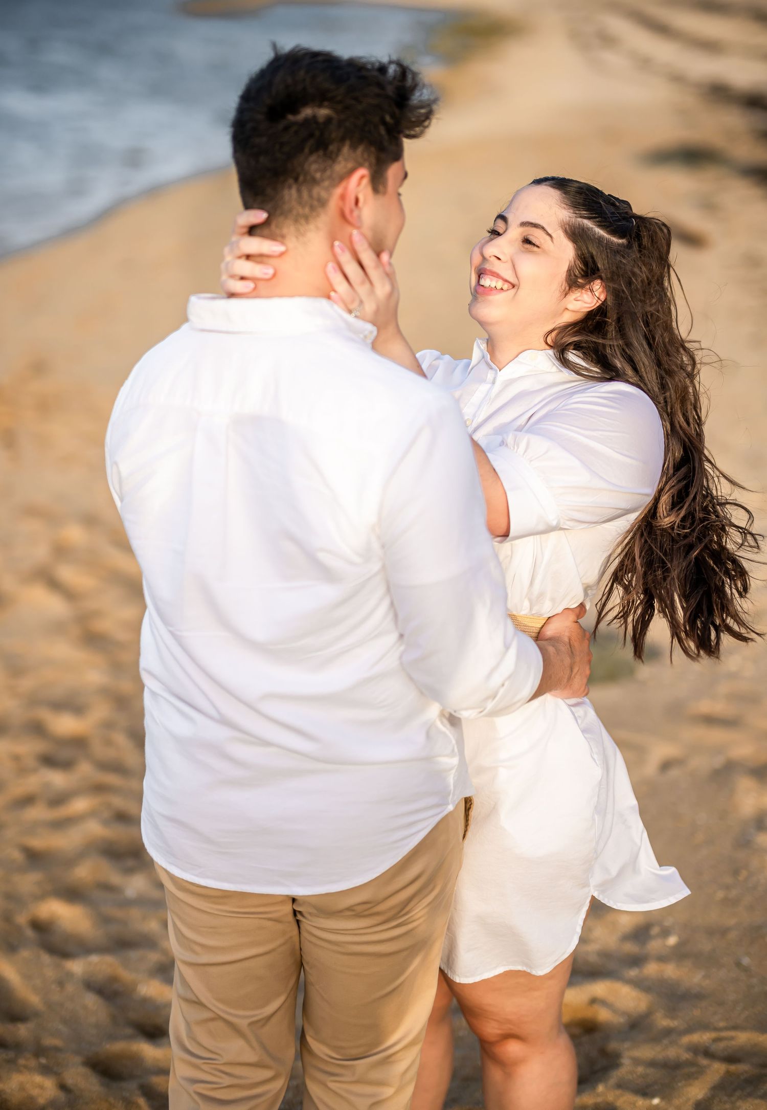 Couple sharing a romantic moment while dancing on sandy beach at sunset.