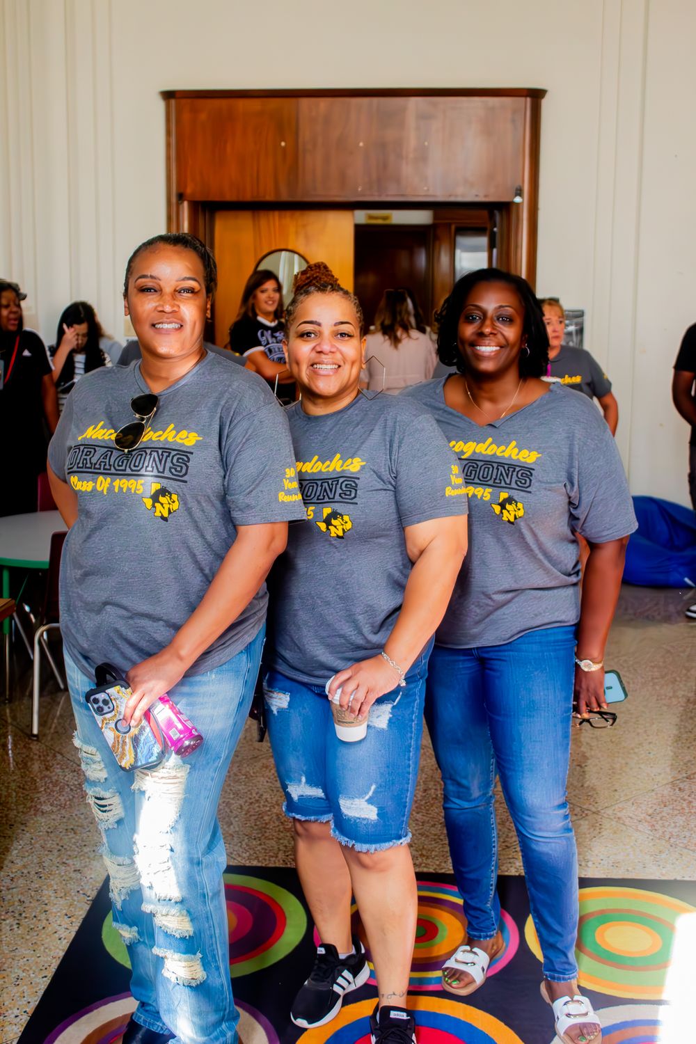 A group of people wearing matching gray t-shirts and jeans pose together in an indoor setting.