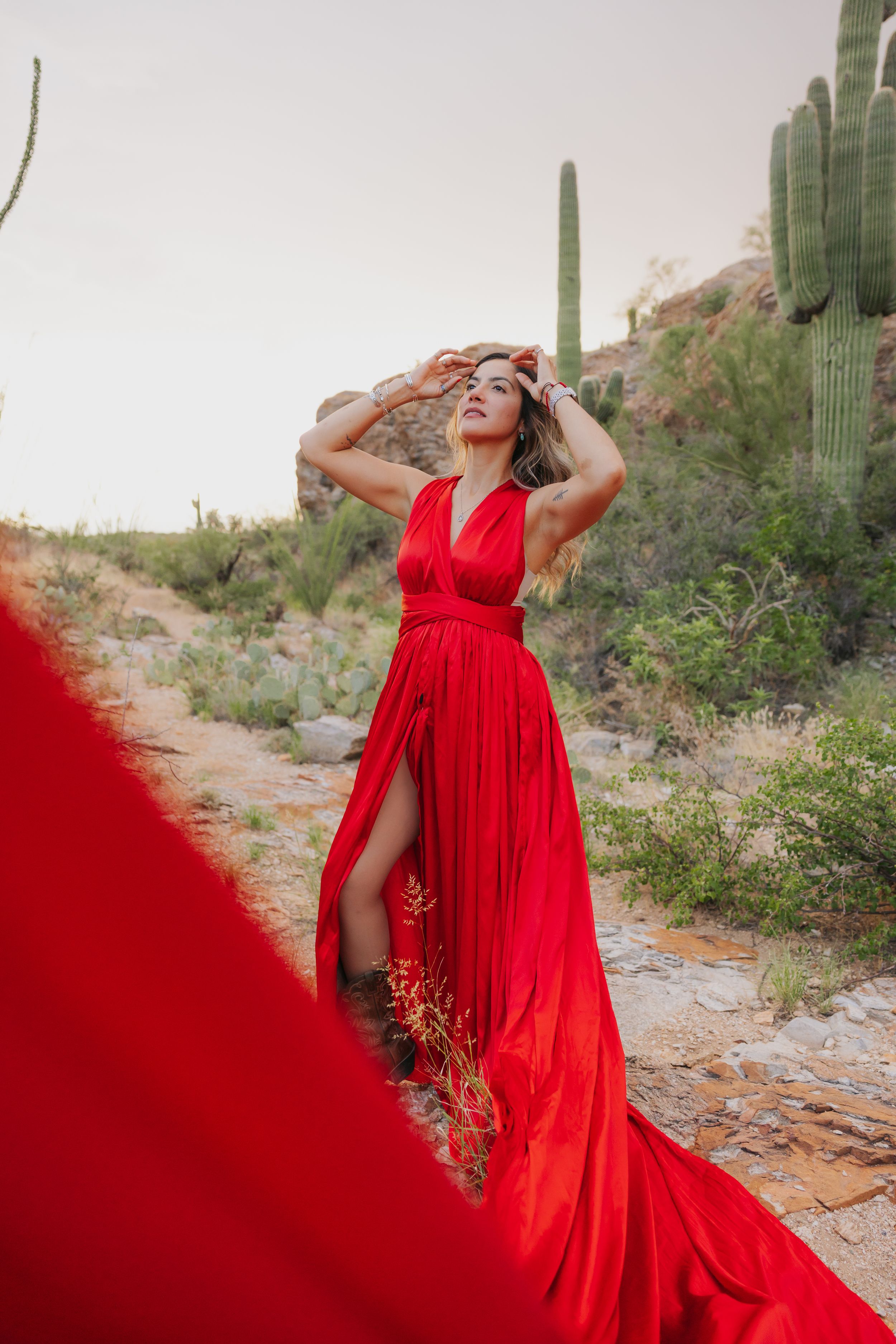 A flowing red dress creates movement against the desert landscape with saguaro cacti.