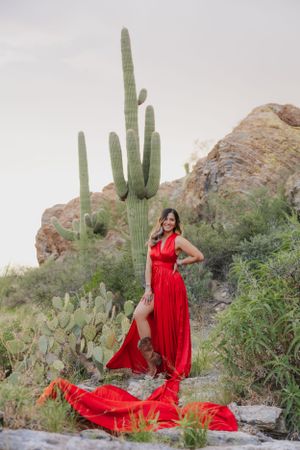 Vibrant red gown billows in the wind among towering saguaro cacti in an Arizona desert landscape.