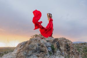 Red fabric dances in wind during desert photoshoot with dramatic rock formations.
