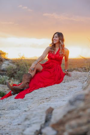 Red dress contrasts beautifully with desert rocks during golden hour photography session.