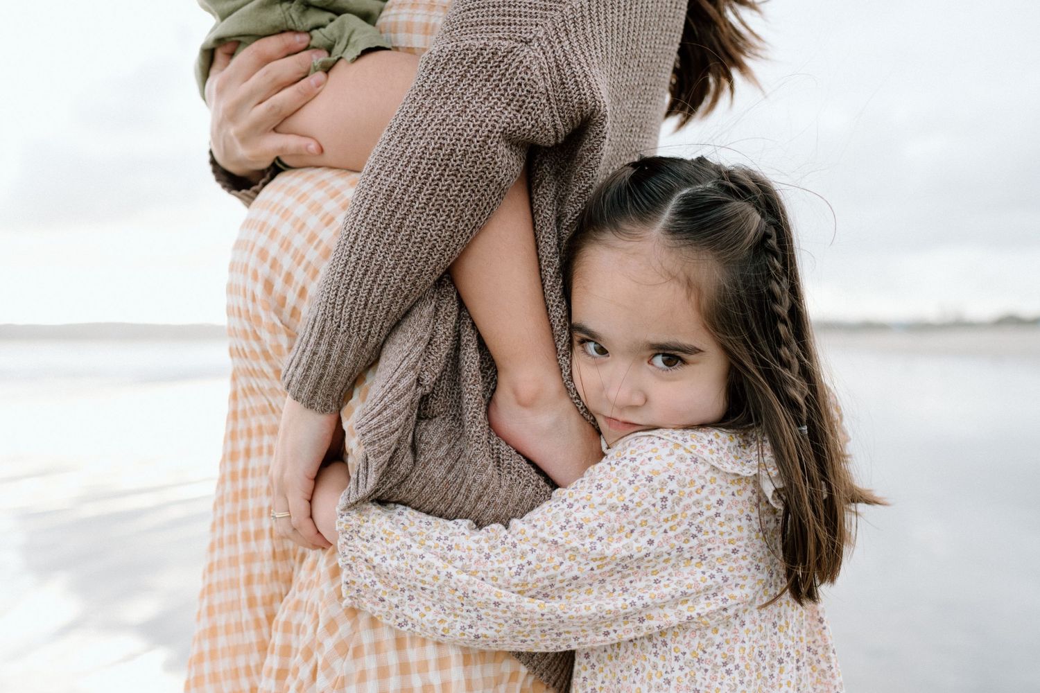 Tender embrace captured between parent and child wearing soft knit sweaters during maternity photoshoot in San Diego.