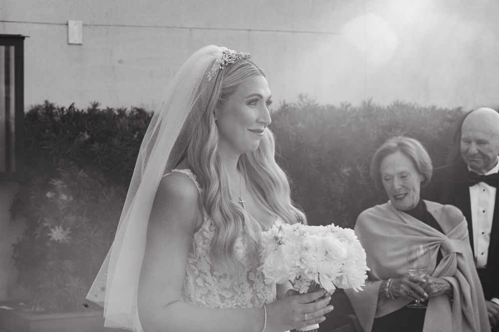 Elegant outdoor wedding ceremony with guests seated on white chairs at sunset.