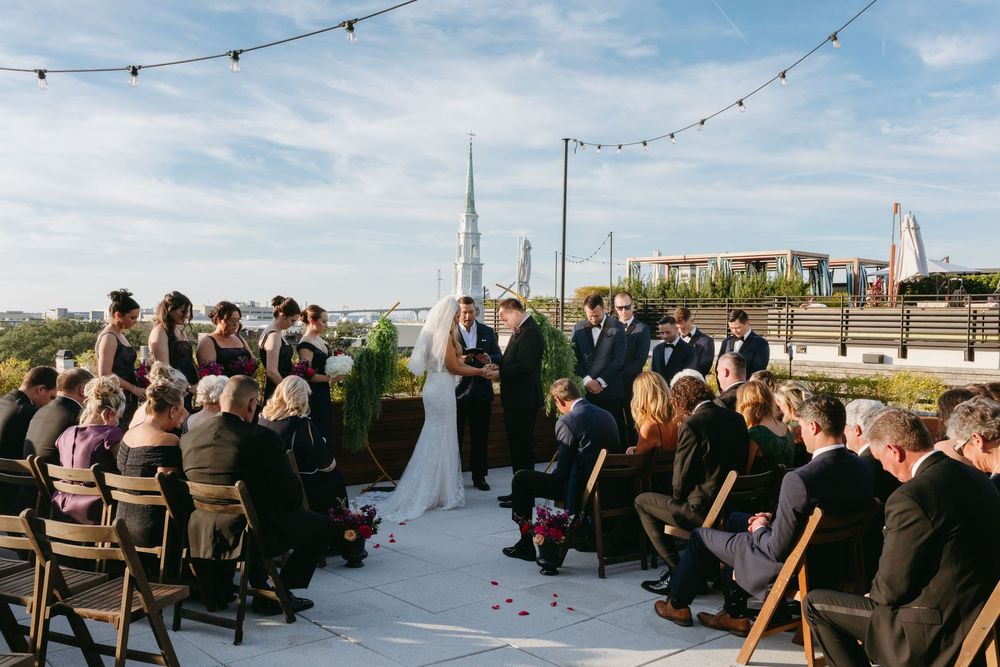 Outdoor wedding ceremony setup with string lights and rows of chairs against a blue sky.