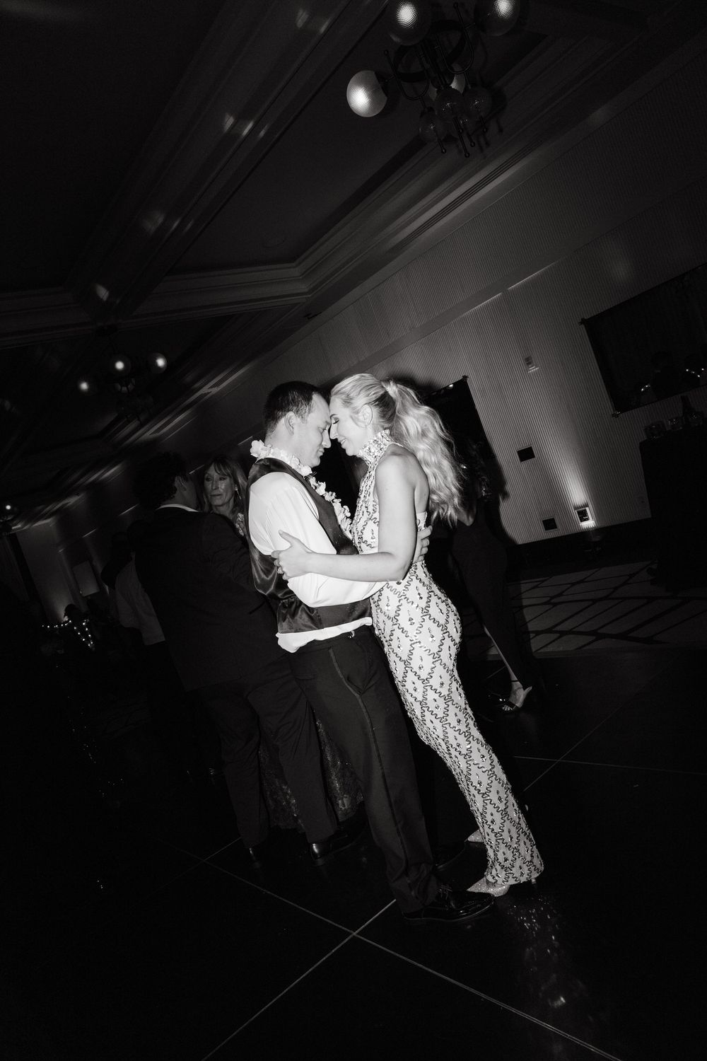 Couple shares romantic dance moves in a dimly lit reception venue.