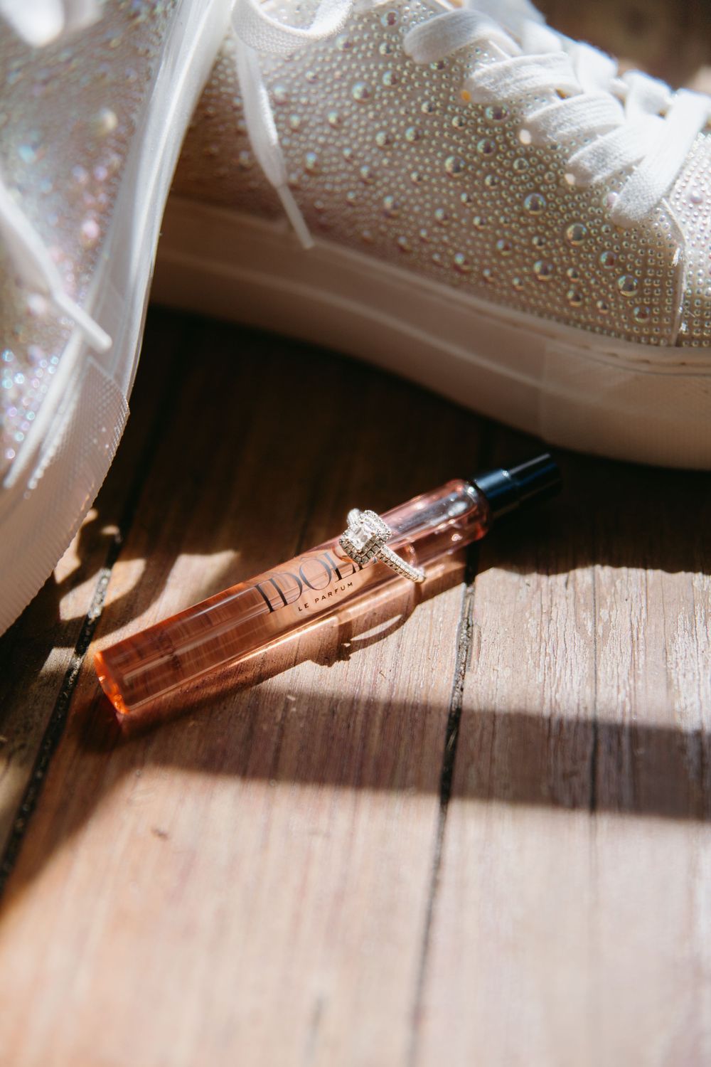White sneakers and rose gold pen displayed on rustic wooden surface in natural lighting.