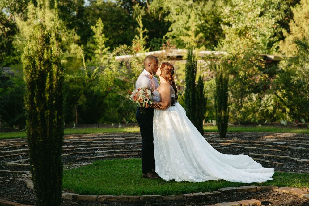 Wedding couple poses on wooden boardwalk surrounded by lush greenery.