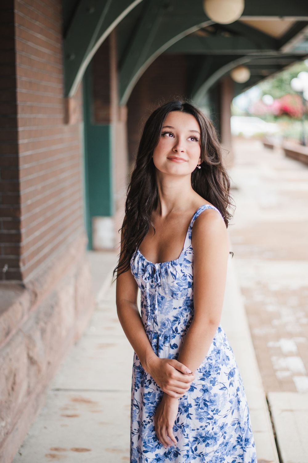 A floral blue and white summer dress is photographed against a brick wall background.