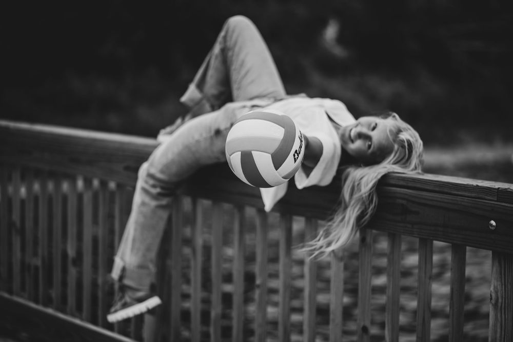 Black and white photo of person lying back on railing in dramatic pose.