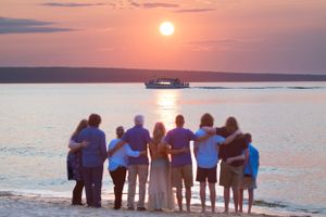Group watching sunset over water while standing together on beach. miners beach