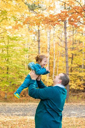 Joyful playtime moment against vibrant autumn foliage with yellow and orange leaves in a forest setting.