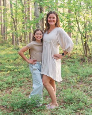 A family enjoying a playful moment together in a sunlit forest setting with green foliage in the background.