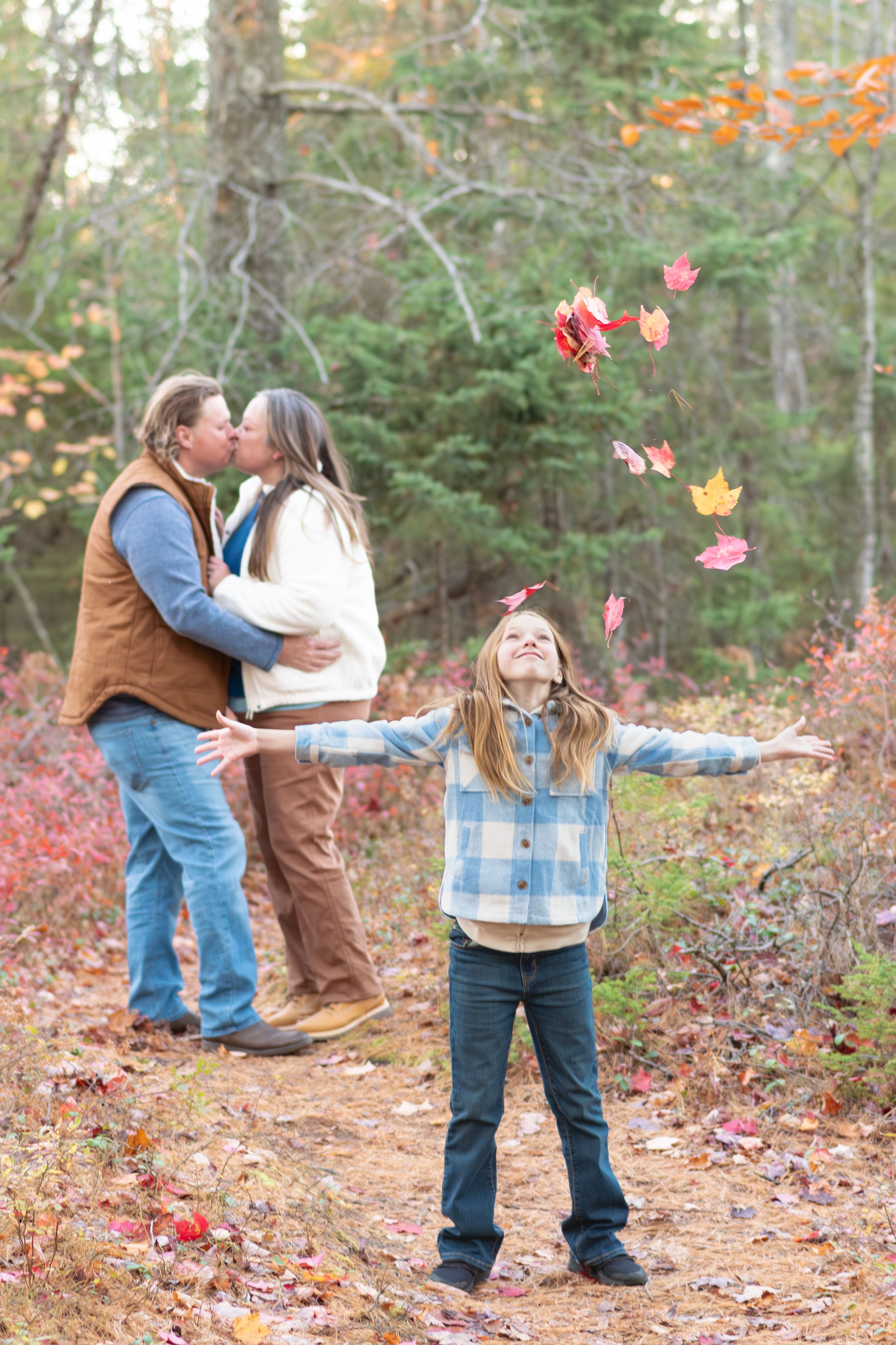 A romantic autumn engagement photo session in a wooded area with fallen leaves and natural lighting.