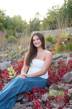 A casual outdoor portrait among vibrant red foliage and rocks during golden hour.
