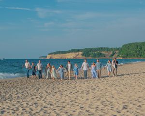 A panoramic sequence of beachgoers gathering along a sandy shoreline with blue ocean and sky in the background.