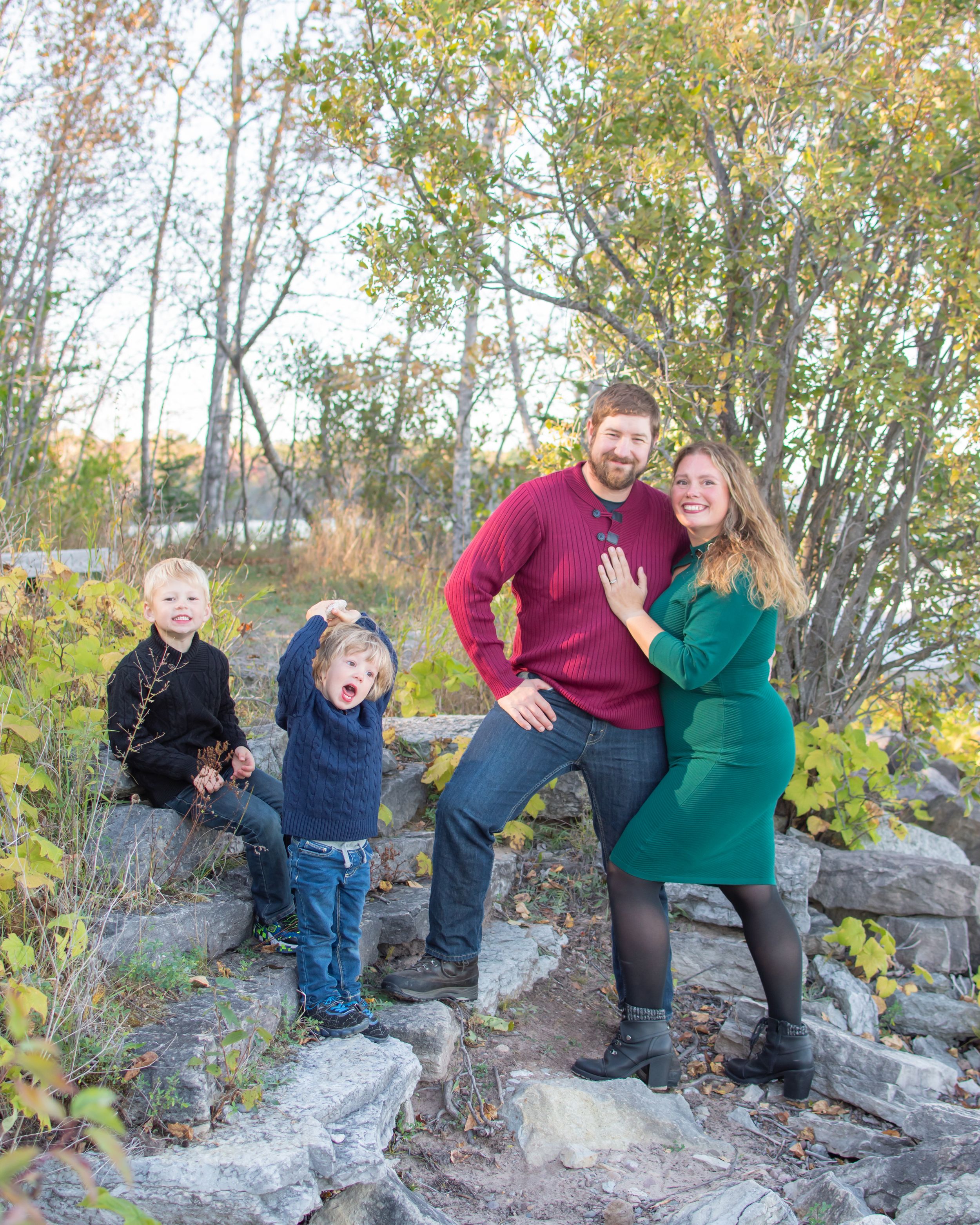 A family group poses playfully on rocky terrain surrounded by autumn foliage in a series of candid outdoor shots.