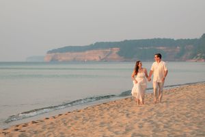 People walking on a sandy beach at sunset with cliffs in the background.