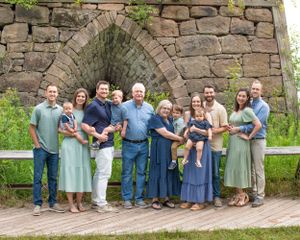 Large family gathering posed in front of stone archway wall. bay furnace