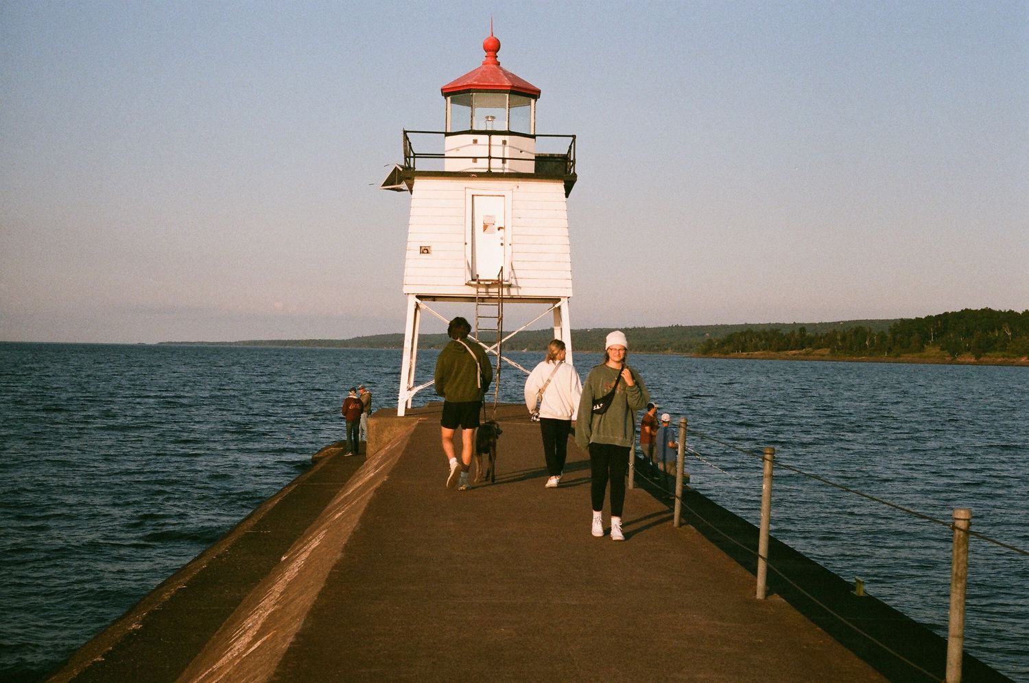 The small lighthouse in Two Harbours Minnesota with friends walking towards it on film